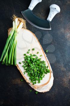 green onion, fresh  onion and knife on kitchen table