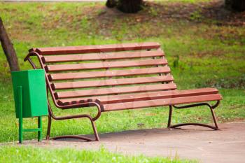 Old brown wooden bench in the park on a background of green grass in the shadow
