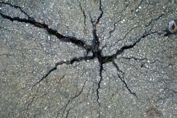 Forces of nature and ecology against the industry concept: old gray asphalt pavement with big cracks in pavement surface closeup view