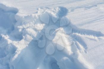 Snow print of human body silhouette shaped on the white fresh snow under winter day sun light