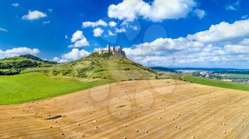 View of Spissky hrad and a field with round bales in Slovakia, Central Europe