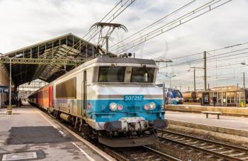 NARBONNE, FRANCE - JANUARY 06: Passenger train hauled by electric locomotive at Narbonne station on January 6, 2014. SNCF operates 198 locomotive of the class BB 7200