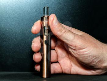 Hand with electronic cigarette on a dark background