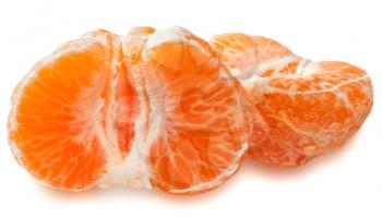 Slices of a ripe tangerine on the peel on a white background