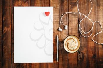 Blank branding template on vintage wooden table background. Blank white paper, letterhead, pen, headphones and red heart. Mock-up for branding identity. Top view.