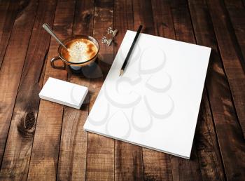 Blank paperwork template: letterhead, coffee cup and pencil on vintage wooden table background. Mock-up for ID. Blank stationery template for design portfolios. Top view.