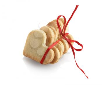 Cookies in the shape of hearts, tied with red ribbon on white background. Isolated with clipping path.