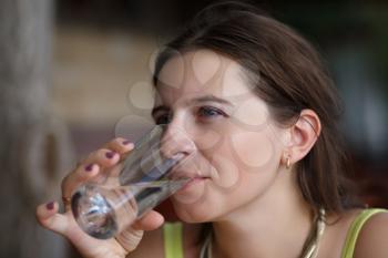 Cute young woman drinks water from a glass beaker. Shallow depth of field. Focus on the model's face.