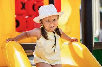 Child in a white hat and a yellow T-shirt playing in the playground. Shallow depth of field. Focus on the model's face.