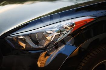 Close-up car headlight of powerful modern black car with glare.