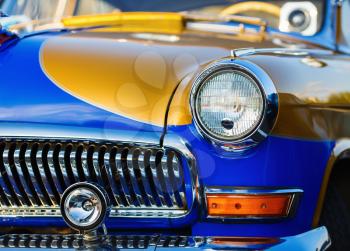 Close-up of vintage classic car. Bright colored retro car. headlight of a vintage car. Selective focus on the car's headlight.