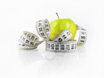 Fresh green apple and measuring tape. Symbol of diet and healthy lifestyle. Shallow depth of field. Focus on the measuring tape.