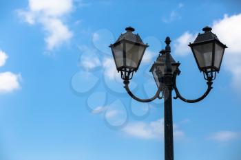 Old vintage lamppost on the blue sky background. Space for text.