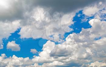 White cumulus clouds against a bright blue sky on a sunny day.