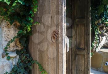 Old weathered wooden door with rusty handle. Rustic door. Shallow depth of field. Selective focus.