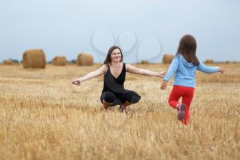 Happy family. Joyful mom and her little daughter on a field of hay and straw bales. Shallow depth of field. Selective focus on mother.