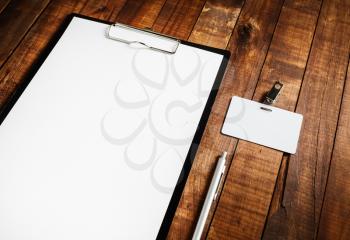 Photo of blank letterhead, badge and pen on vintage wooden table background. Blank ID template. Branding mock-up for your design.