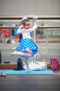 Little ballerina practicing in a dance class. Child girl posing at ballet barre in a dance class. Preschool child taking dance lessons. Ballet school. Shallow depth of field. Selective focus.