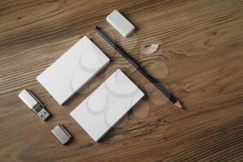 Photo of blank stationery set. Bank business cards, pencil, eraser and flash drive on wood table background. Responsive design mockup. Top view.