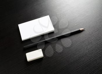 Photo of blank stationery set on black wooden table background. Bank business card, pencil and eraser. Template for ID. Responsive design mockup. Top view.