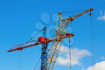 Tower crane and mobile construction crane against blue sky background