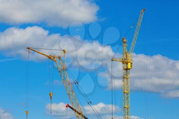 Yellow tower crane and mobile construction crane against blue sky background