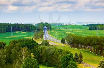 Green fields, trees, road and sky with clouds. Summer landscape. Minsk region, Belarus