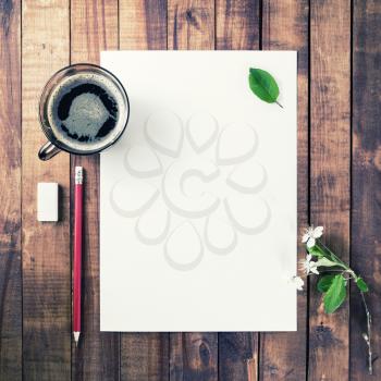 Responsive design template. Blank letterhead, coffee cup, pencil, eraser, flowers and green leaves on vintage wood background. Mockup for branding identity with plenty of copy space.