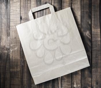 Photo of blank paper shopping bag on wooden table background. Top view.
