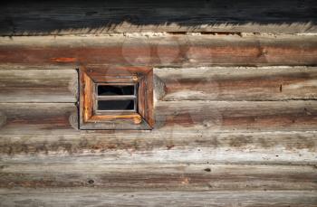 Small wood window in the wall of old wooden log house. Space for text.