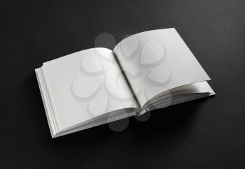 Photo of opened blank square book on black paper background.