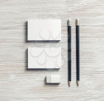 Blank stationery set on light wooden background. Business cards, pencils and eraser. Flat lay.