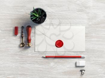 Blank retro envelope with red wax seal and retro stationery on light wood table background. Mockup for your design. Flat lay.