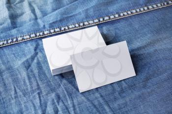 Blank paper business cards on denim background. Mockup for branding identity.