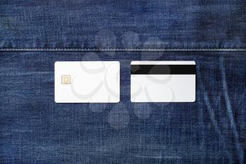 Two blank white plastic credit cards on denim background. Chip cards. Front and back view. Flat lay.