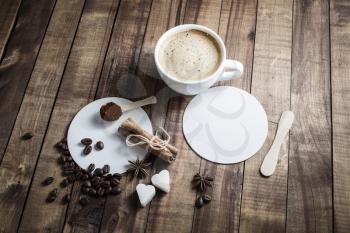 Coffee on wooden table background. Coffee cup, cinnamon sticks, coffee beans, anise, sugar, spoon and coasters