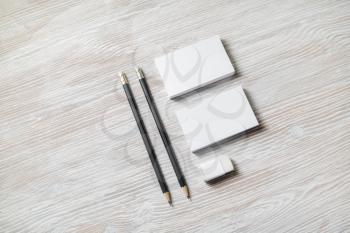 Photo of blank business cards, pencils and eraser on light wood table background.