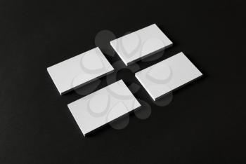 Photo of four blank business cards stacks on black paper background.