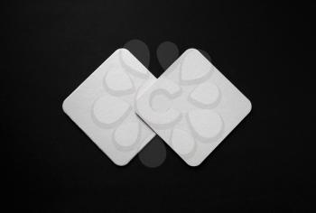 Two blank square beer coasters mockup on black background.