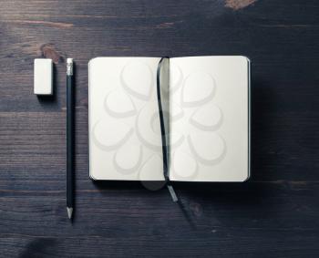 Blank opened notebook, pencil and eraser on wooden background. Template for graphic designers portfolios. Flat lay.