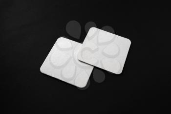 Two blank square beer coasters on black background. Responsive design mockup.