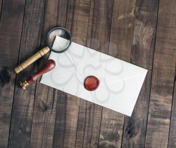 Blank envelope, stamp and magnifier on wooden background. Flat lay.