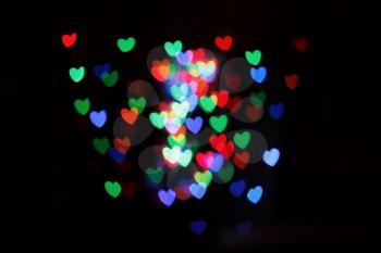 Hearts form bokeh. Multicolored blurred hearts on a black background.