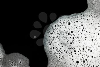 Soap foam with bubbles on black background. Shampoo in water.