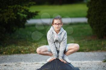 Girl child posing in a frog pose in the park. Child on the playground. Selective focus.