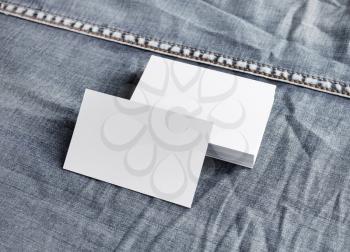 Photo of blank white business cards on denim background.