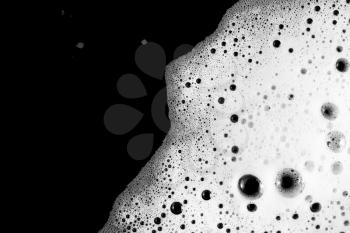 Soap sud. Foam with bubbles on black background. Detergent in water. Flat lay.