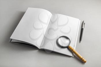 Book with with blank pages, magnifier and pencil on paper background.