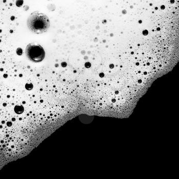 Foam with bubbles on black background. Soap sud. Detergent in water. Abstract soapy texture. Flat lay.