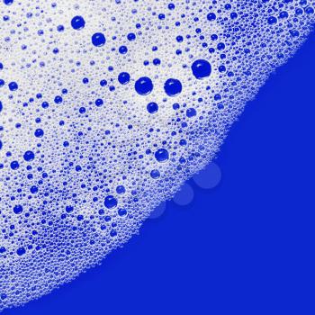 Soap sud. Foam with bubbles on blue background. Detergent in water. Flat lay.